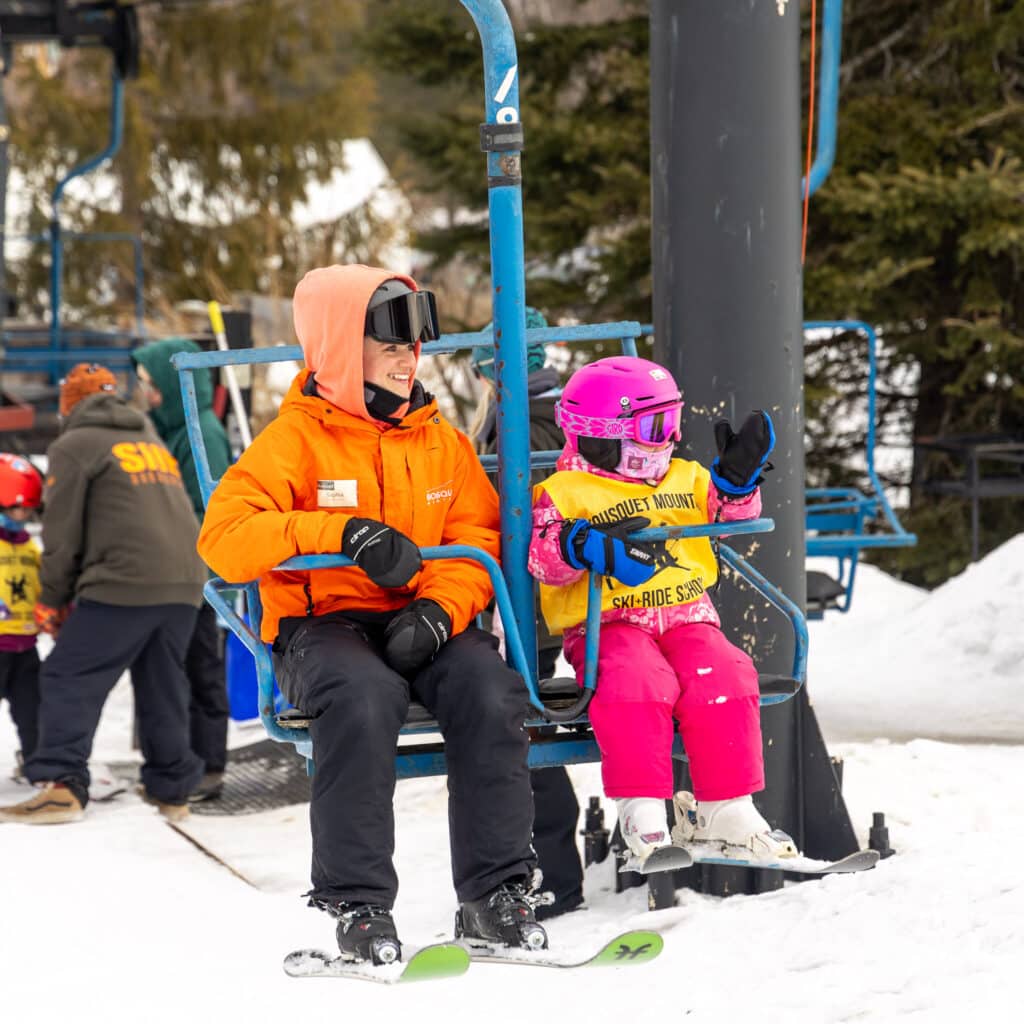 Young girl riding the beginner chairlift at Bousquet mountain with an instructor