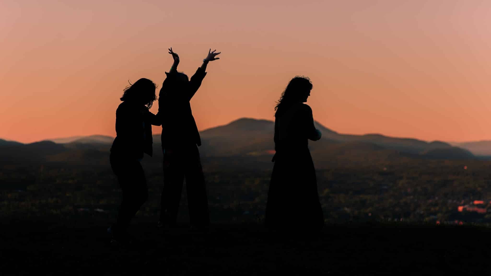 beautiful scenic experience at the top of bousquet mountain. three women danicng in front of a sunset